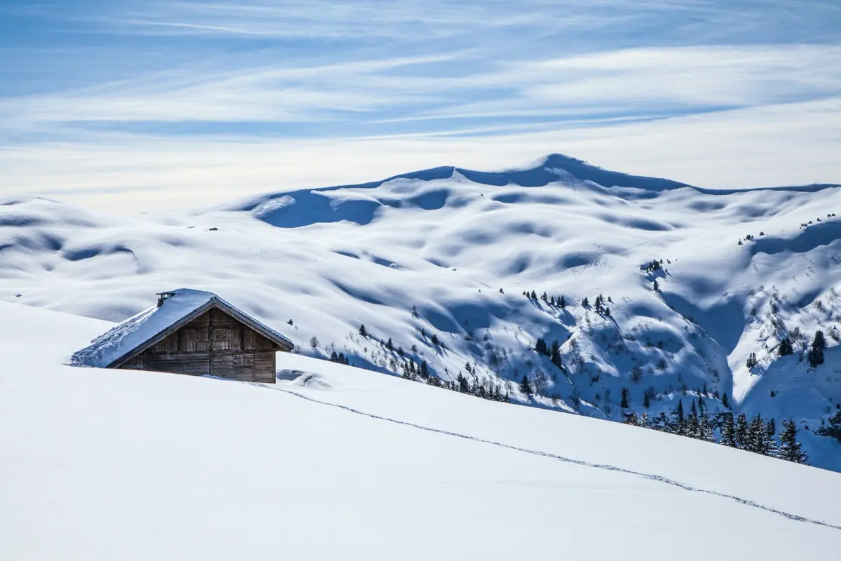 Solitary wooden cabin in a snow-covered alpine setting